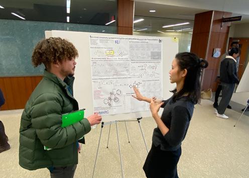 Two KU Pharmacy students review a graduate student research poster