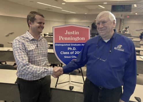Distinguished Graduate Award recipient Justin Pennington is congratulated by Associate Dean John Stobaugh, Pennington’s former KU mentor.