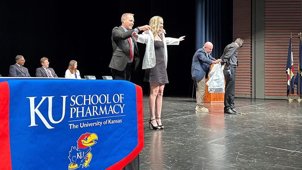 Faculty help students don their white coats.